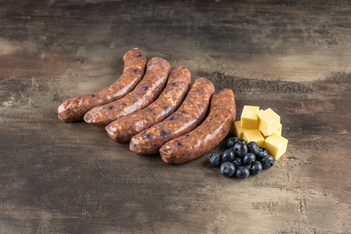Rohe Salsiccia im Naturdarm mit sichtbaren Blaubeeren im groben Brät, von der Seite fotografiert