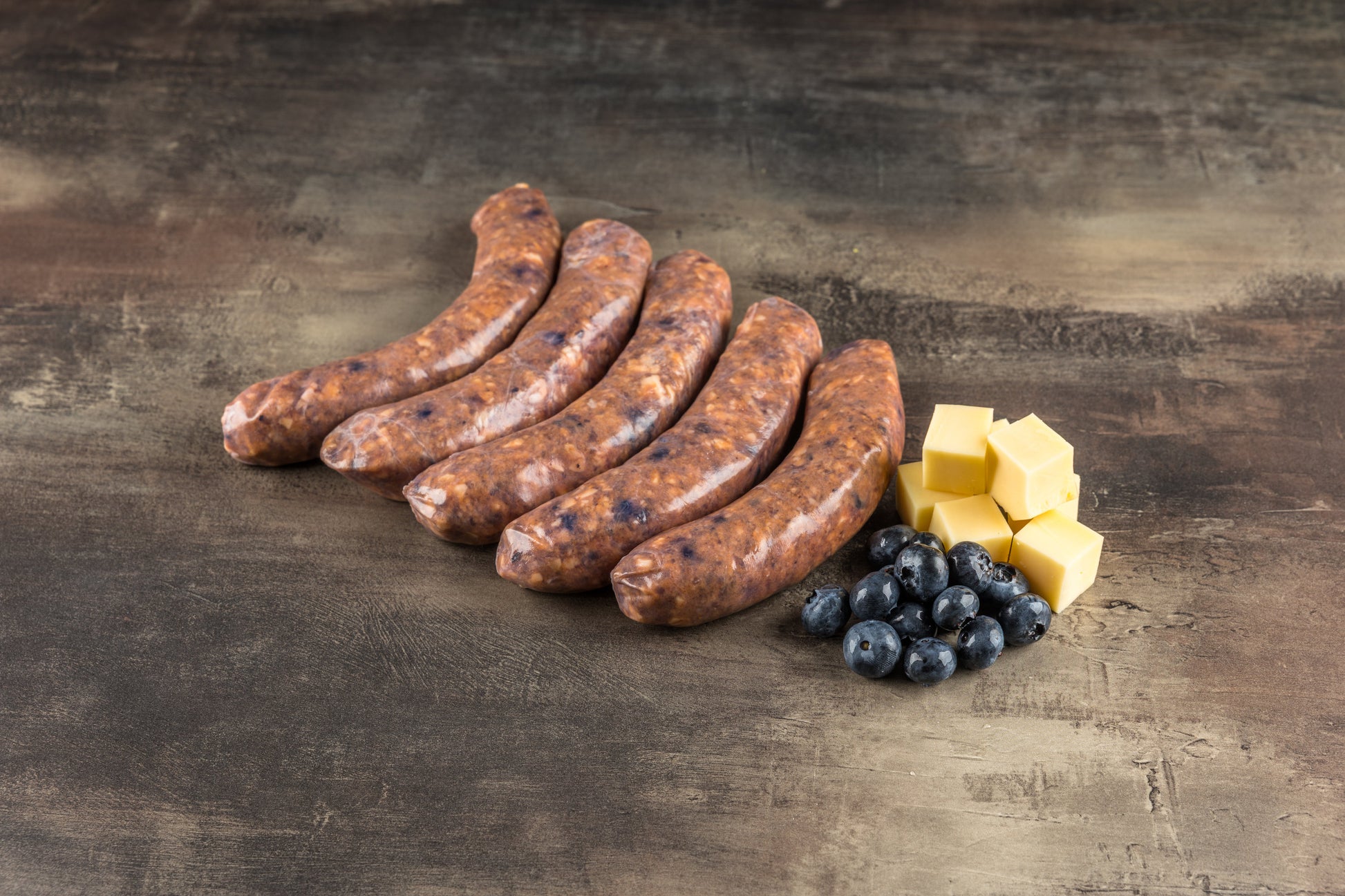 Rohe Salsiccia im Naturdarm mit sichtbaren Blaubeeren im groben Brät, von der Seite fotografiert