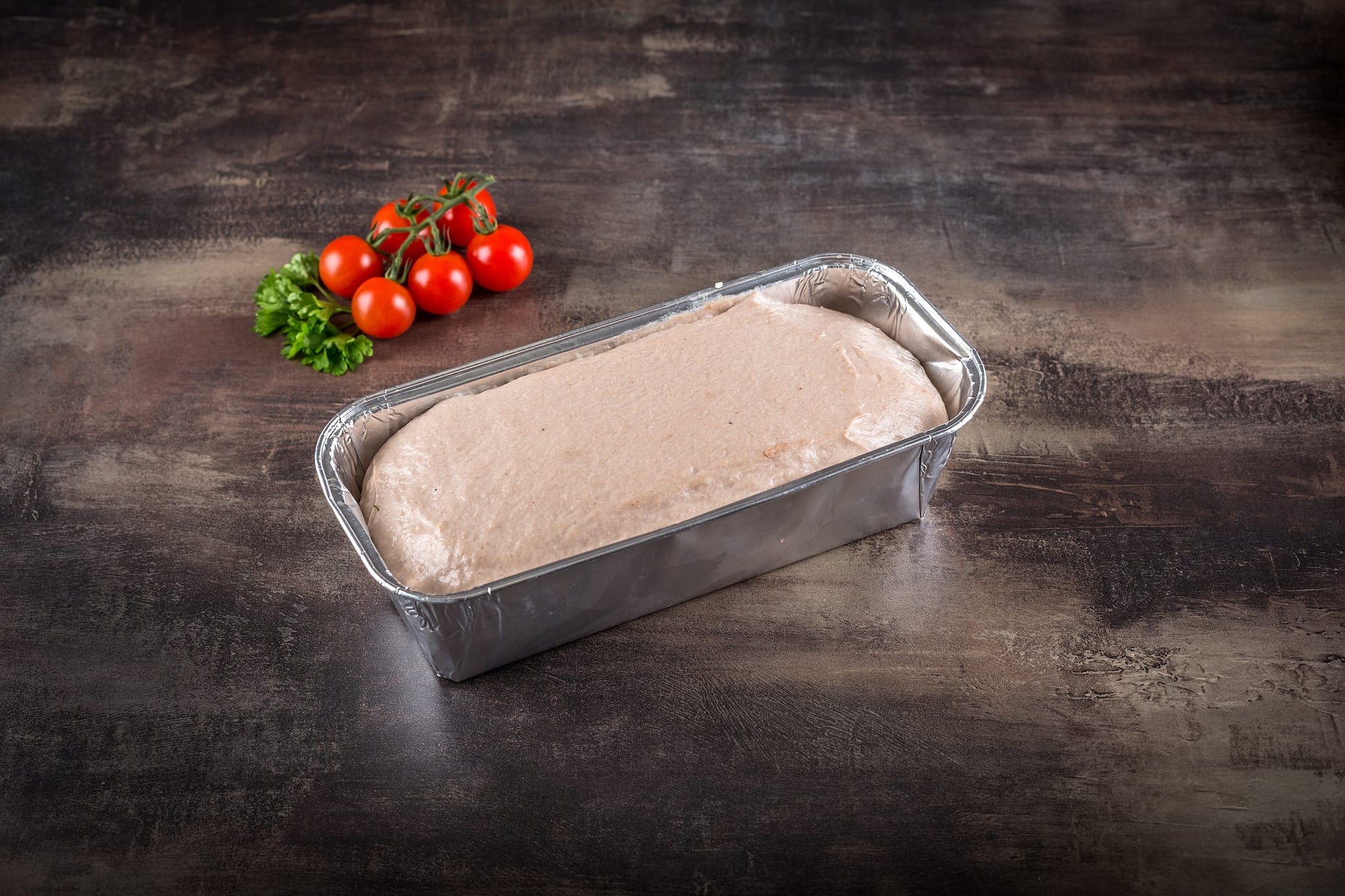 Feiner Fleischkäse roh in der Alu-Backform, fertig zum Aufbacken im Backofen